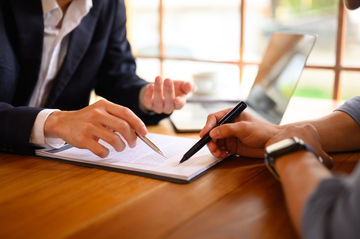 Asesor corporativo revisando documentación contractual con cliente en oficina profesional
